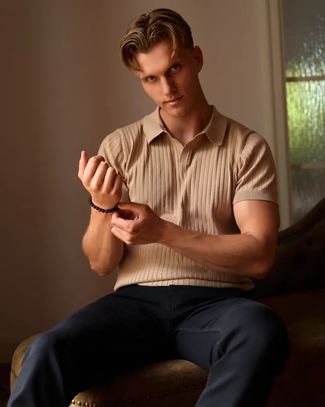 Portret Andrzeja w beżowej koszulce polo siedzącego na kanapie w ciepłym świetle, sesja portretowa Wrocław