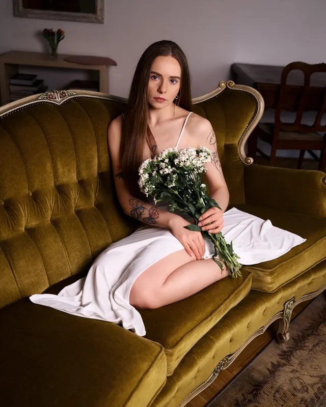 Julia siedząca na zielonej kanapie z bukietem białych kwiatów, sesja portretowa Łódź