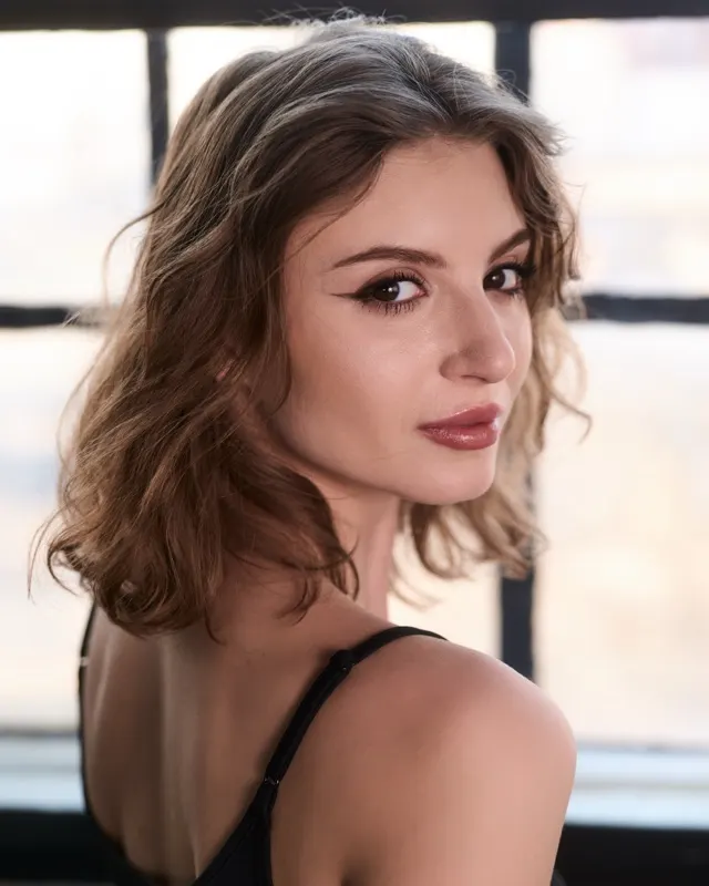 Portret Natalii z falowanymi włosami przy industrialnym oknie, sesja portretowa Wrocław